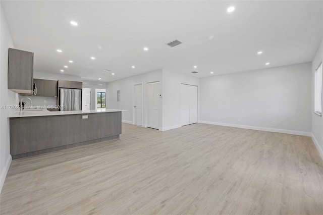 unfurnished living room featuring light hardwood / wood-style floors and sink