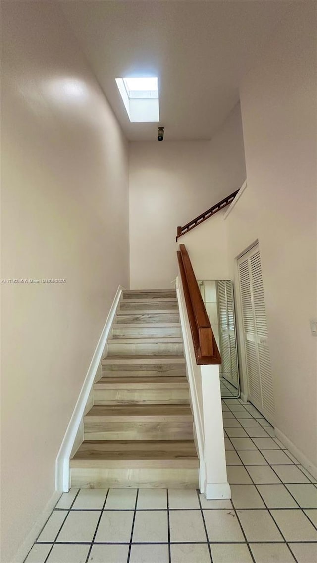 stairs featuring tile patterned floors and a skylight