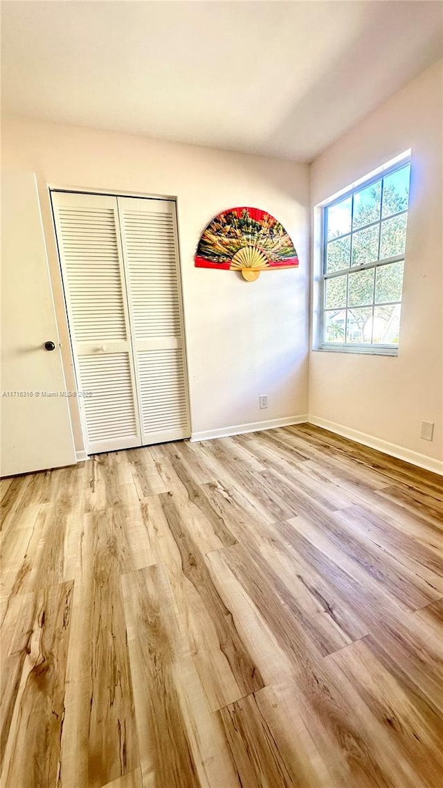 unfurnished bedroom featuring light wood-type flooring and a closet