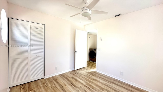 unfurnished bedroom featuring washer / clothes dryer, ceiling fan, a closet, and light hardwood / wood-style floors