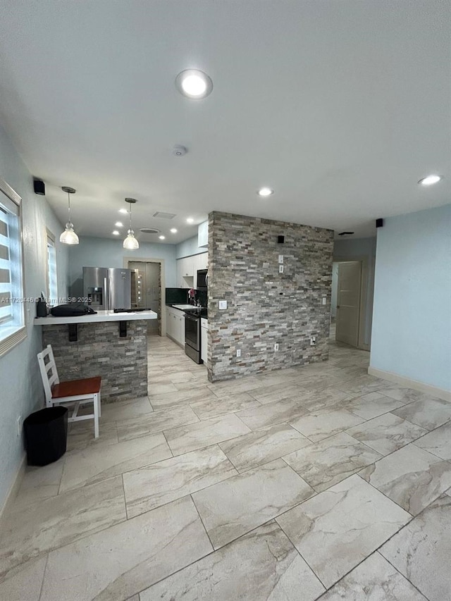 kitchen featuring a breakfast bar area, white cabinetry, hanging light fixtures, appliances with stainless steel finishes, and kitchen peninsula