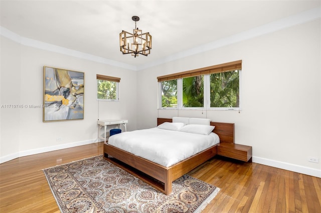 bedroom with hardwood / wood-style floors, an inviting chandelier, and ornamental molding