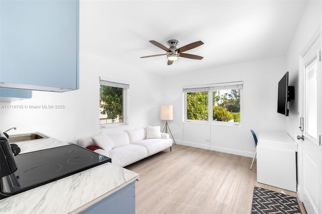 living room featuring sink, a healthy amount of sunlight, light hardwood / wood-style flooring, and ceiling fan