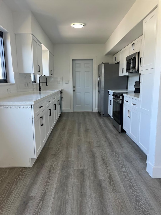 kitchen with dark wood-type flooring, sink, decorative backsplash, appliances with stainless steel finishes, and white cabinetry