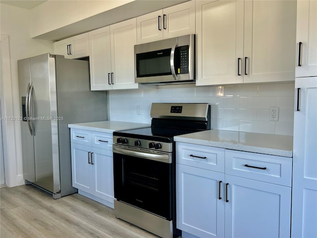 kitchen with light stone countertops, stainless steel appliances, backsplash, white cabinets, and light wood-type flooring