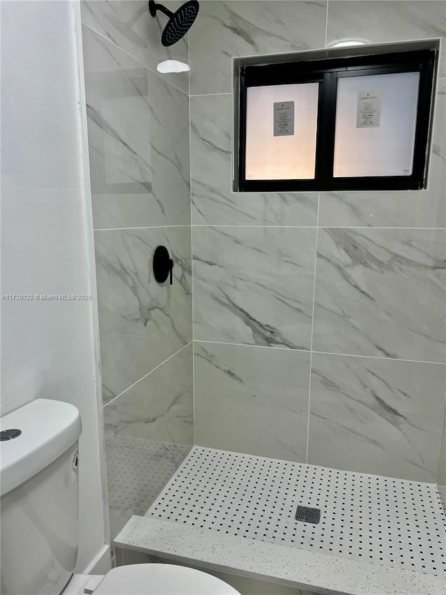 bathroom featuring a tile shower and toilet