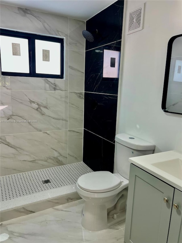 bathroom featuring tiled shower, vanity, and toilet