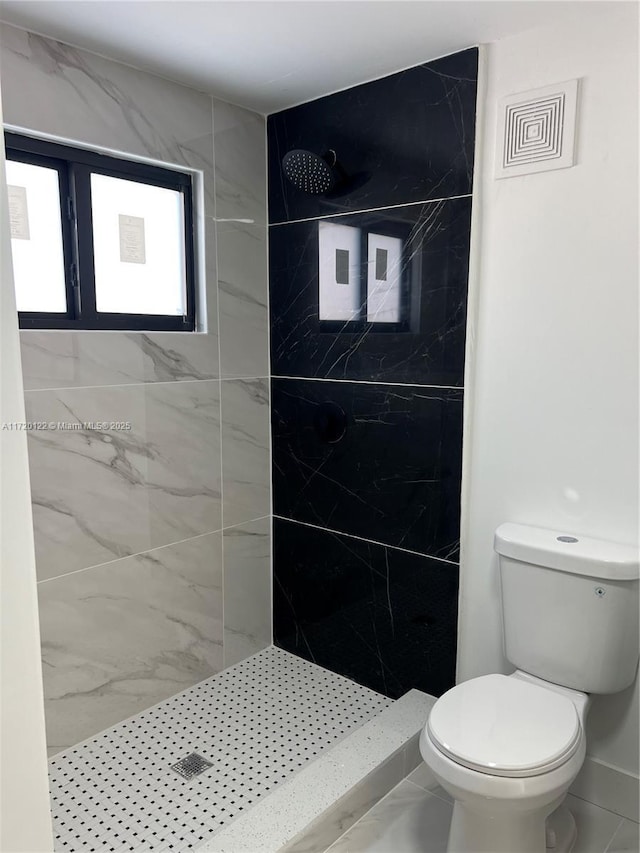 bathroom featuring a tile shower and toilet