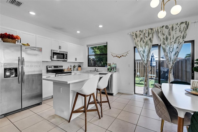 kitchen with white cabinets, a kitchen island, hanging light fixtures, and appliances with stainless steel finishes