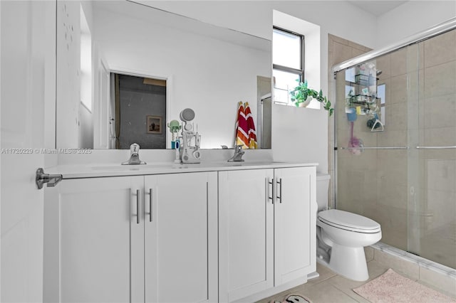 bathroom with tile patterned flooring, vanity, a shower with shower door, and toilet