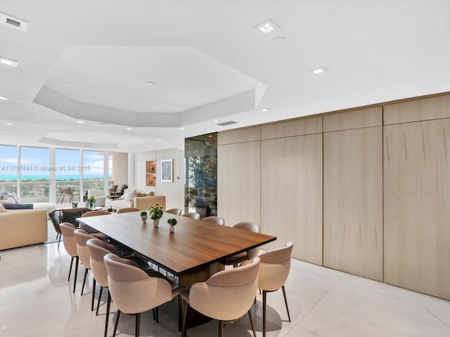 dining space with a wall of windows, light tile patterned floors, and a tray ceiling