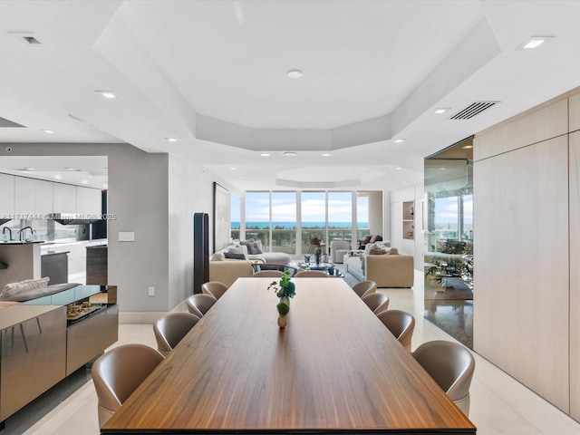 tiled dining space featuring a tray ceiling and expansive windows