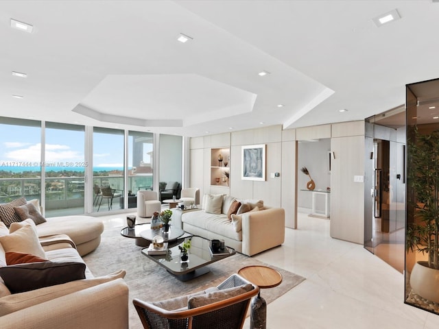 living room featuring a water view, a raised ceiling, and expansive windows