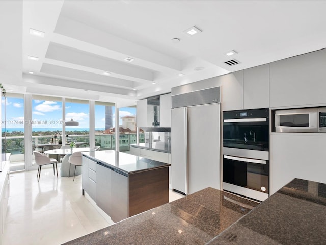 kitchen featuring built in appliances, a center island, floor to ceiling windows, and light tile patterned flooring