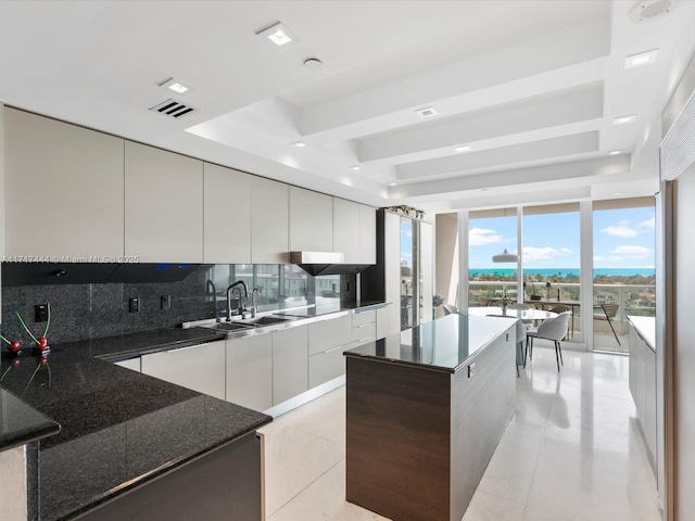 kitchen featuring tasteful backsplash, floor to ceiling windows, a raised ceiling, a center island, and light tile patterned flooring