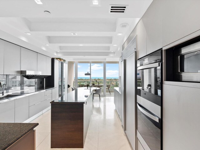 19955 NE 38th Ct Unit 1103, Aventura, FL 33180 - kitchen featuring modern cabinets, a center island, expansive windows, light tile patterned floors, and white cabinetry