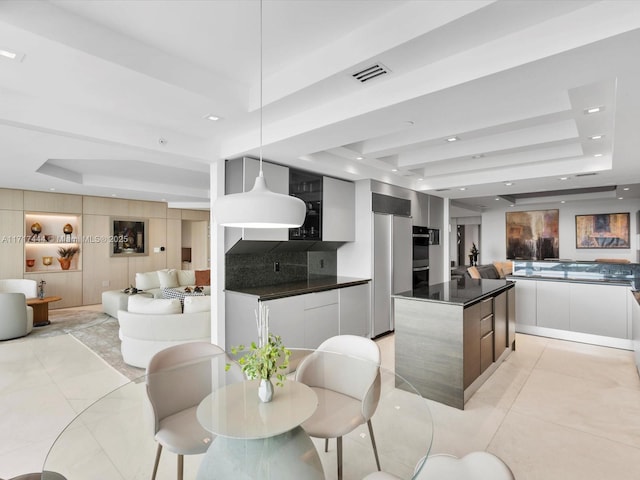 interior space with a center island, hanging light fixtures, light tile patterned floors, a raised ceiling, and white cabinets