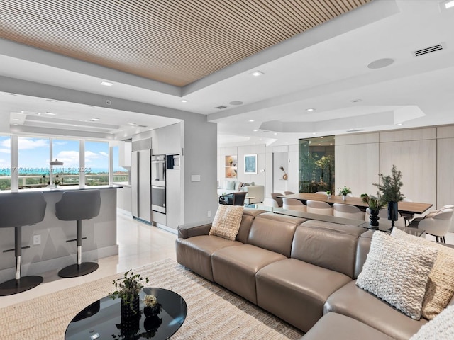 living area with a raised ceiling, light tile patterned flooring, baseboards, and visible vents