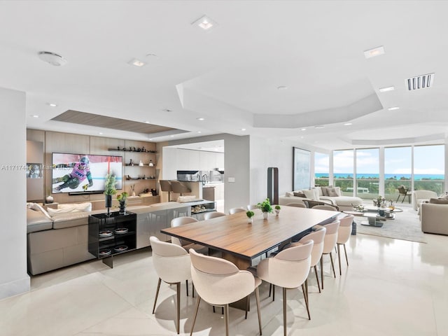 dining area with visible vents, a tray ceiling, expansive windows, recessed lighting, and light tile patterned floors