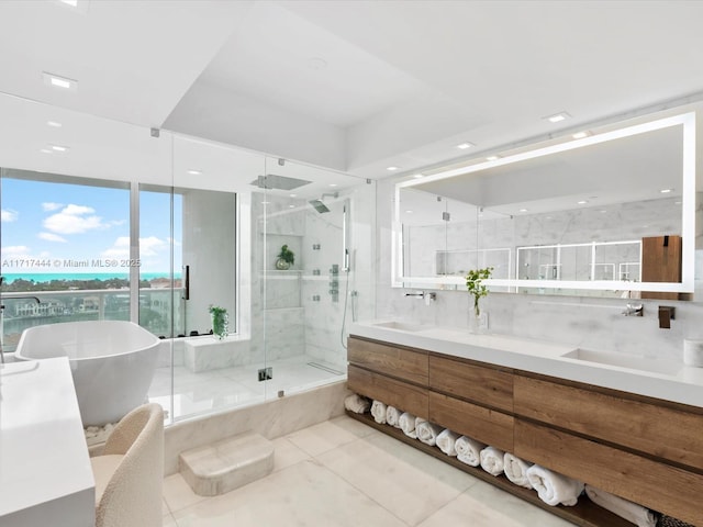 full bathroom with double vanity, a freestanding tub, a stall shower, and a sink