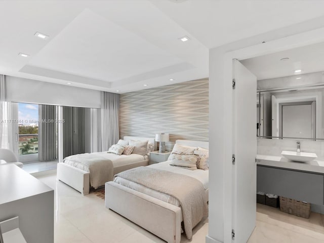 bedroom featuring access to outside, a sink, a tray ceiling, recessed lighting, and an accent wall