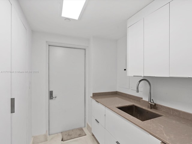 kitchen with white cabinets, light tile patterned floors, and a sink