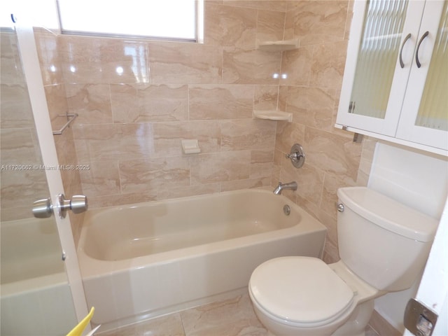 bathroom featuring tiled shower / bath combo and toilet