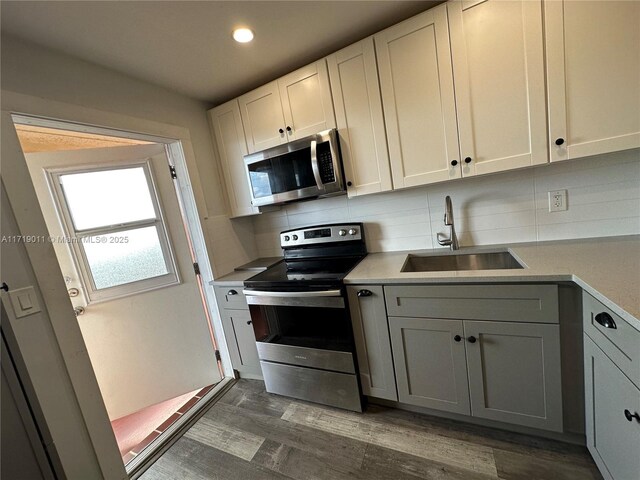 kitchen with appliances with stainless steel finishes, sink, dark hardwood / wood-style flooring, and white cabinetry