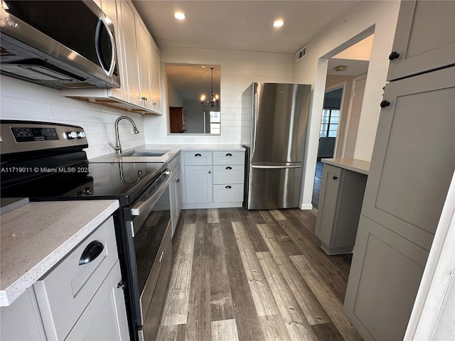 kitchen with appliances with stainless steel finishes, decorative backsplash, dark hardwood / wood-style floors, decorative light fixtures, and sink