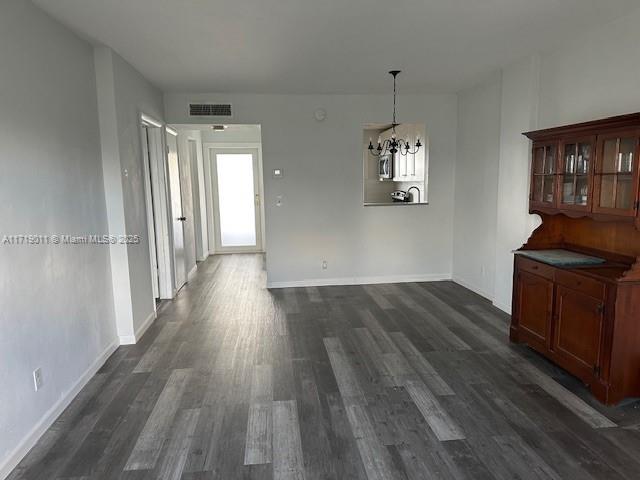 unfurnished dining area with dark hardwood / wood-style flooring, plenty of natural light, and an inviting chandelier