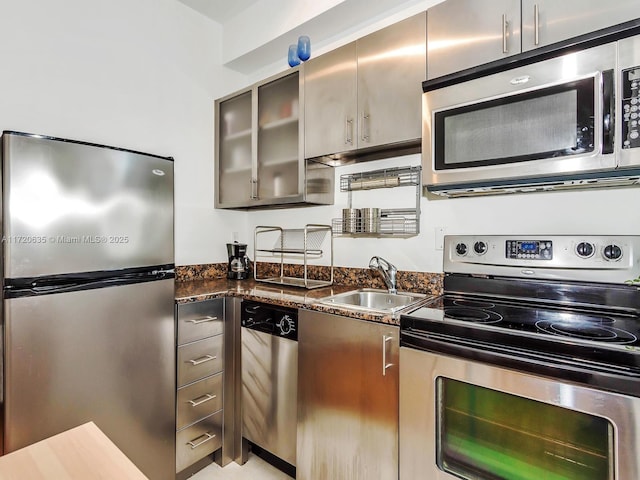 kitchen featuring sink, stainless steel appliances, and dark stone counters