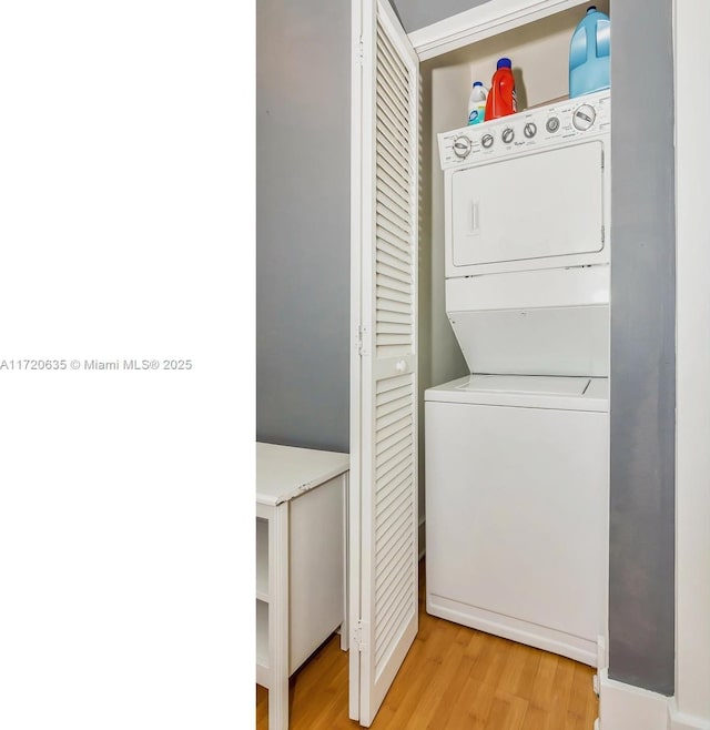 laundry room featuring light wood-type flooring and stacked washer / drying machine