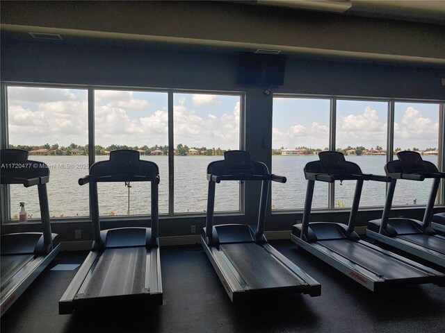 exercise room featuring a water view and plenty of natural light