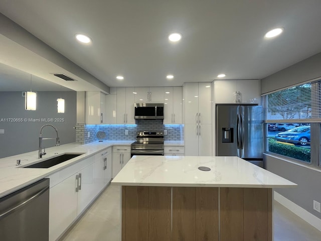 kitchen featuring decorative light fixtures, white cabinets, appliances with stainless steel finishes, and sink