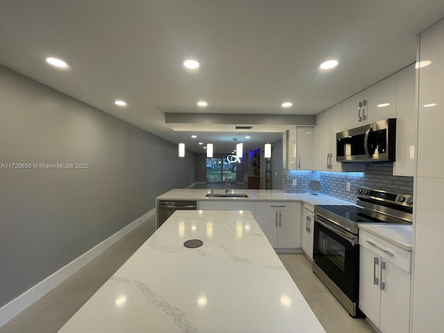 kitchen featuring kitchen peninsula, decorative light fixtures, white cabinets, appliances with stainless steel finishes, and sink