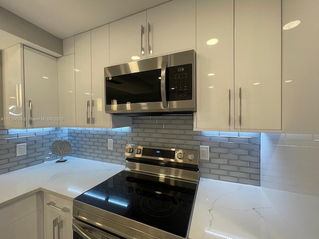 kitchen with backsplash, stainless steel appliances, white cabinets, and light stone counters