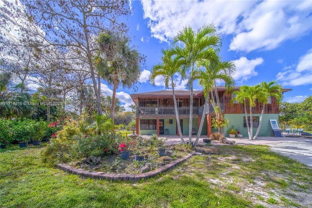 back of house featuring a yard and a balcony