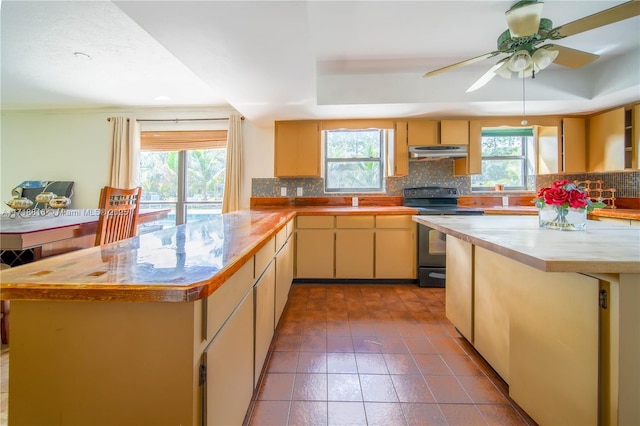 kitchen featuring backsplash, ceiling fan, a kitchen island, and black range with electric cooktop