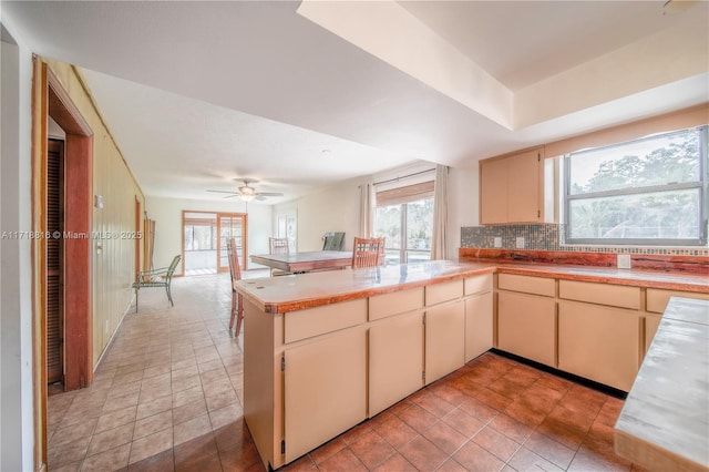 kitchen featuring kitchen peninsula, cream cabinetry, decorative backsplash, and ceiling fan