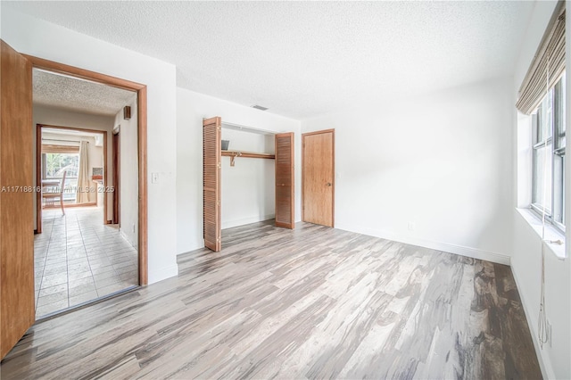 unfurnished bedroom featuring a textured ceiling, light hardwood / wood-style flooring, and a closet