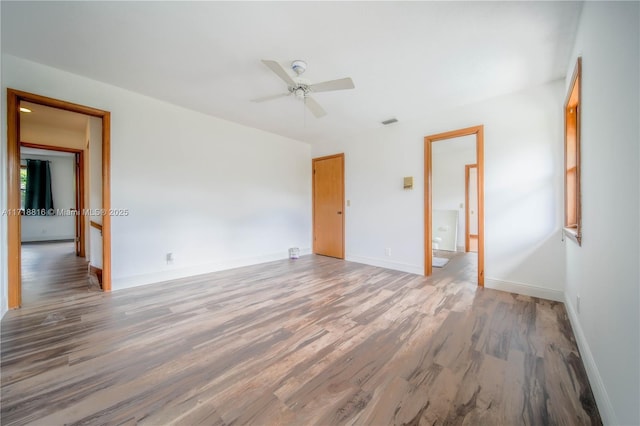unfurnished bedroom featuring multiple windows, hardwood / wood-style flooring, and ceiling fan