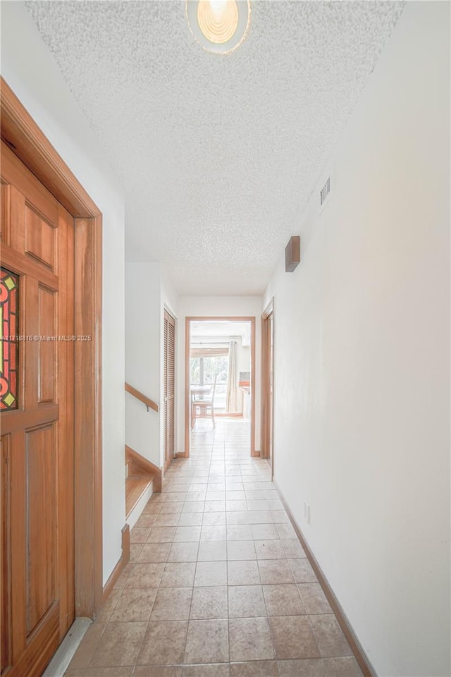 hall featuring a textured ceiling