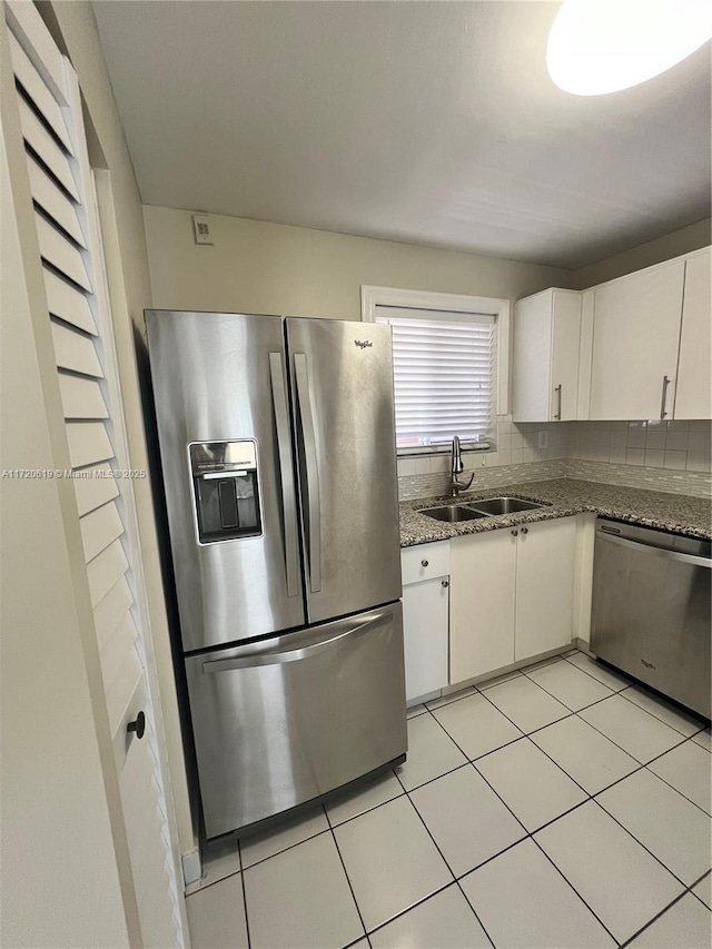 kitchen with stone counters, sink, light tile patterned floors, appliances with stainless steel finishes, and white cabinetry