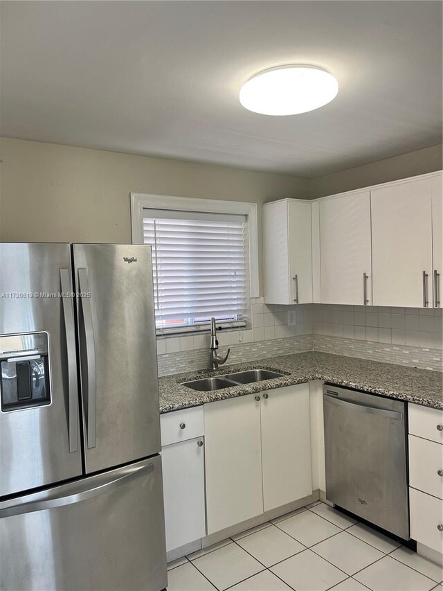 kitchen featuring stainless steel fridge, white cabinetry, light tile patterned floors, and light stone counters