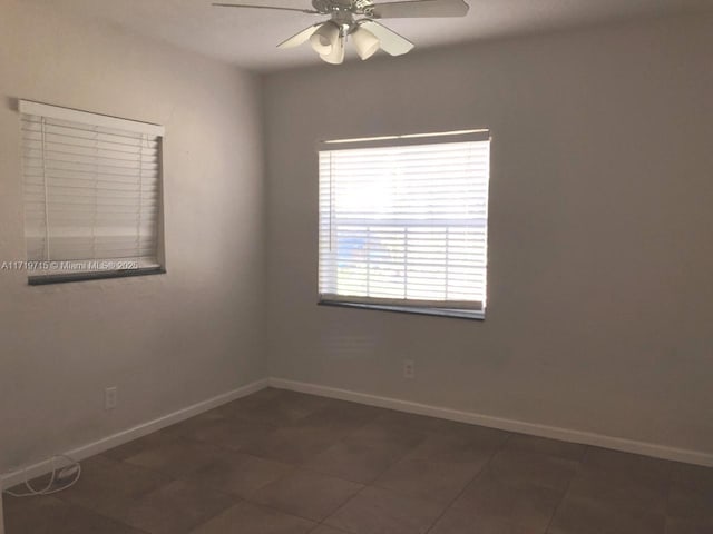 empty room with dark tile patterned flooring and ceiling fan