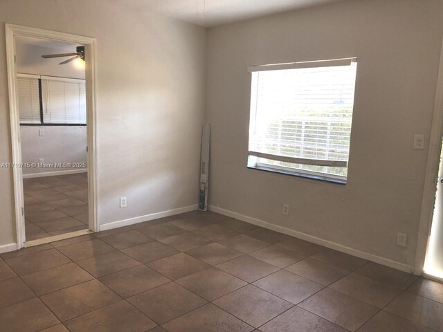 empty room featuring dark tile patterned floors and ceiling fan