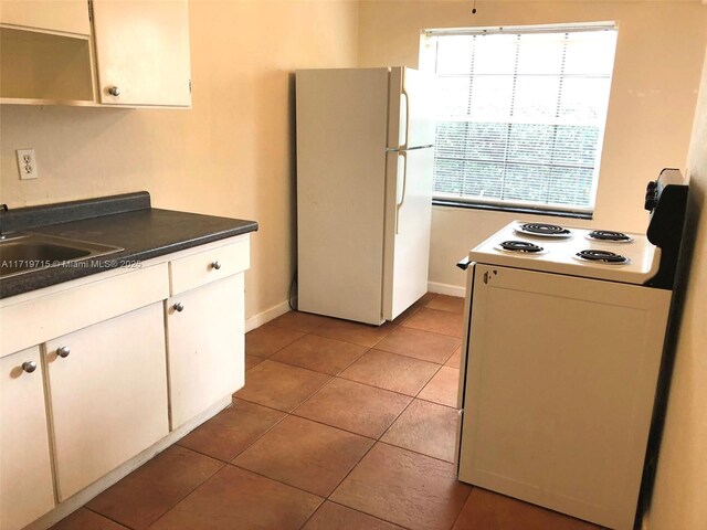 kitchen featuring light tile patterned floors, white cabinets, white appliances, and sink