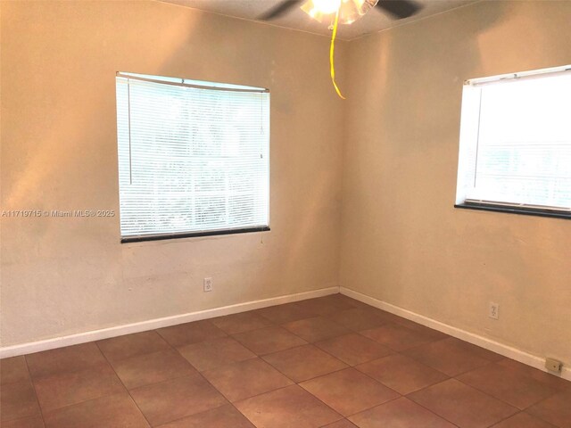 unfurnished room with ceiling fan and dark tile patterned floors