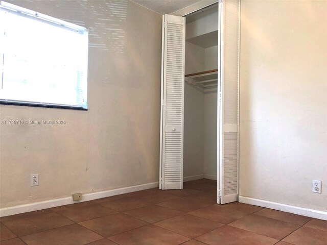 unfurnished bedroom featuring a closet and dark tile patterned floors