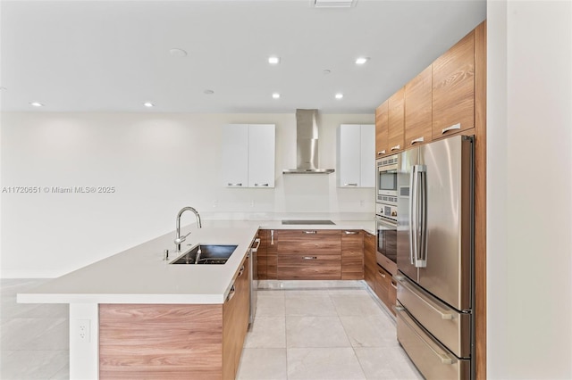 kitchen featuring white cabinets, wall chimney range hood, sink, light tile patterned floors, and appliances with stainless steel finishes